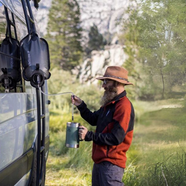 LifeStraw gravity water filter system for outdoor survival and emergency preparedness displayed against a natural backdrop.