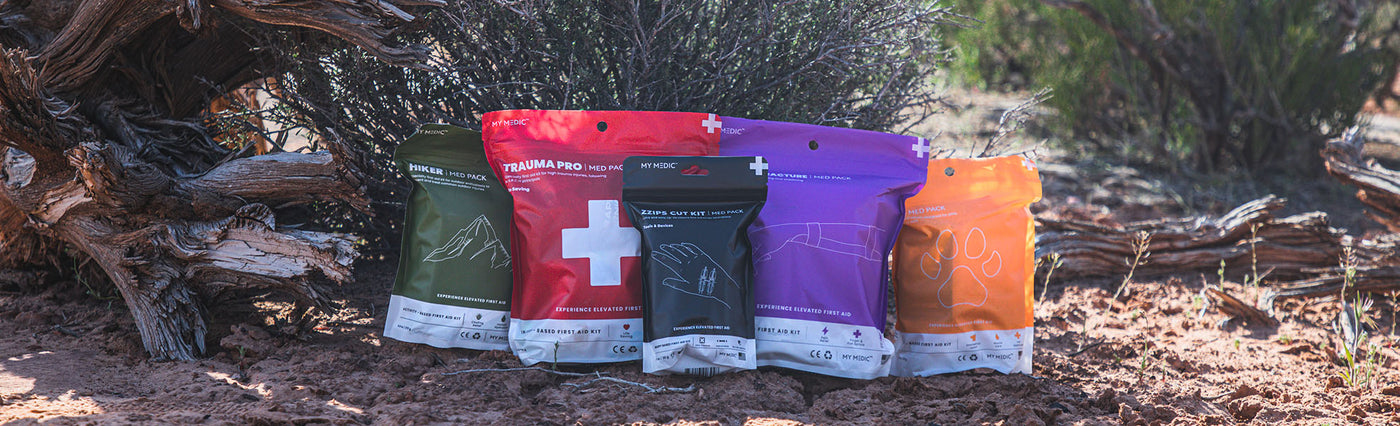 Various medical packs and kits for outdoor survival and emergency preparedness displayed on a rugged background.