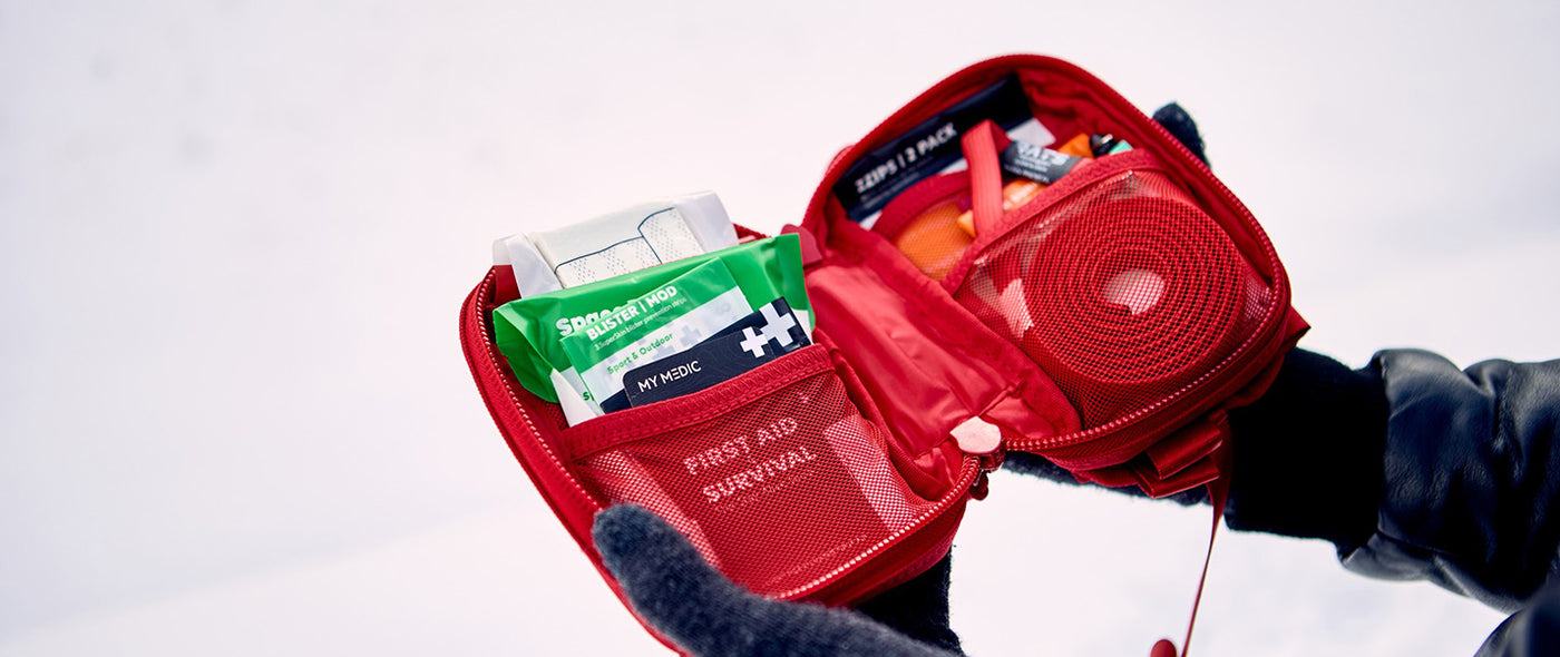Person using MyMedic survival kit in snowy outdoor setting, emphasizing emergency preparedness and winter survival gear.